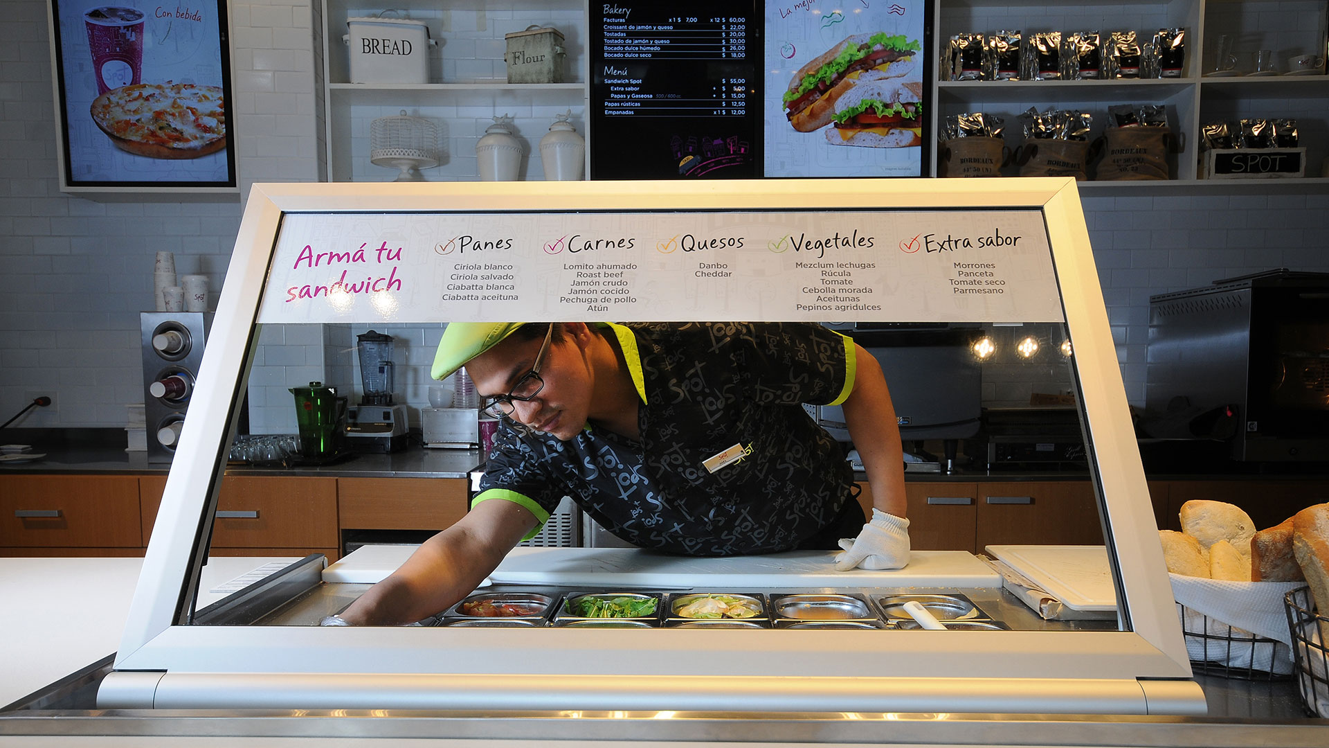 Empleado con uniforme en mostrador de local Spot Café